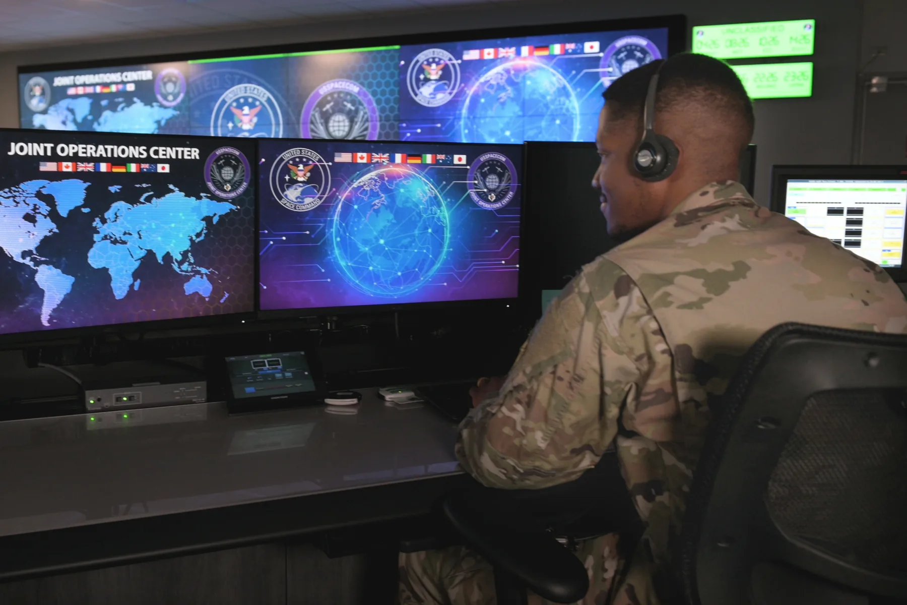 Service member working in a joint operations center with mission displays